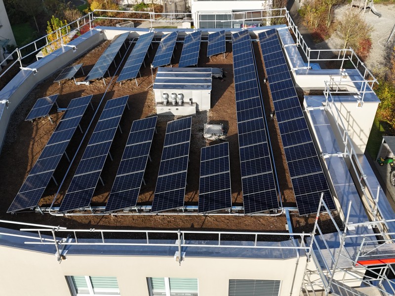 Rooftop solar panel array installed on a flat building roof with metal walkways and equipment in the center for a solar power system