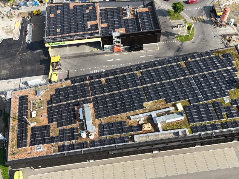 Aerial view of a commercial complex with extensive rooftop solar panels on multiple buildings and surrounding paved areas.