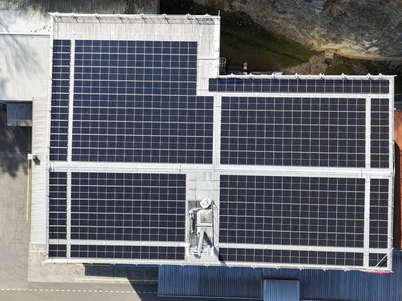 Aerial view of a flat roof covered with large solar panels arranged in a grid.