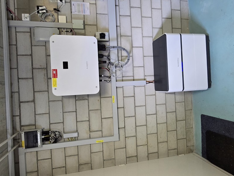 Electrical installation: a wall-mounted white inverter box connected to cables and a secondary white cabinet on a tiled wall.